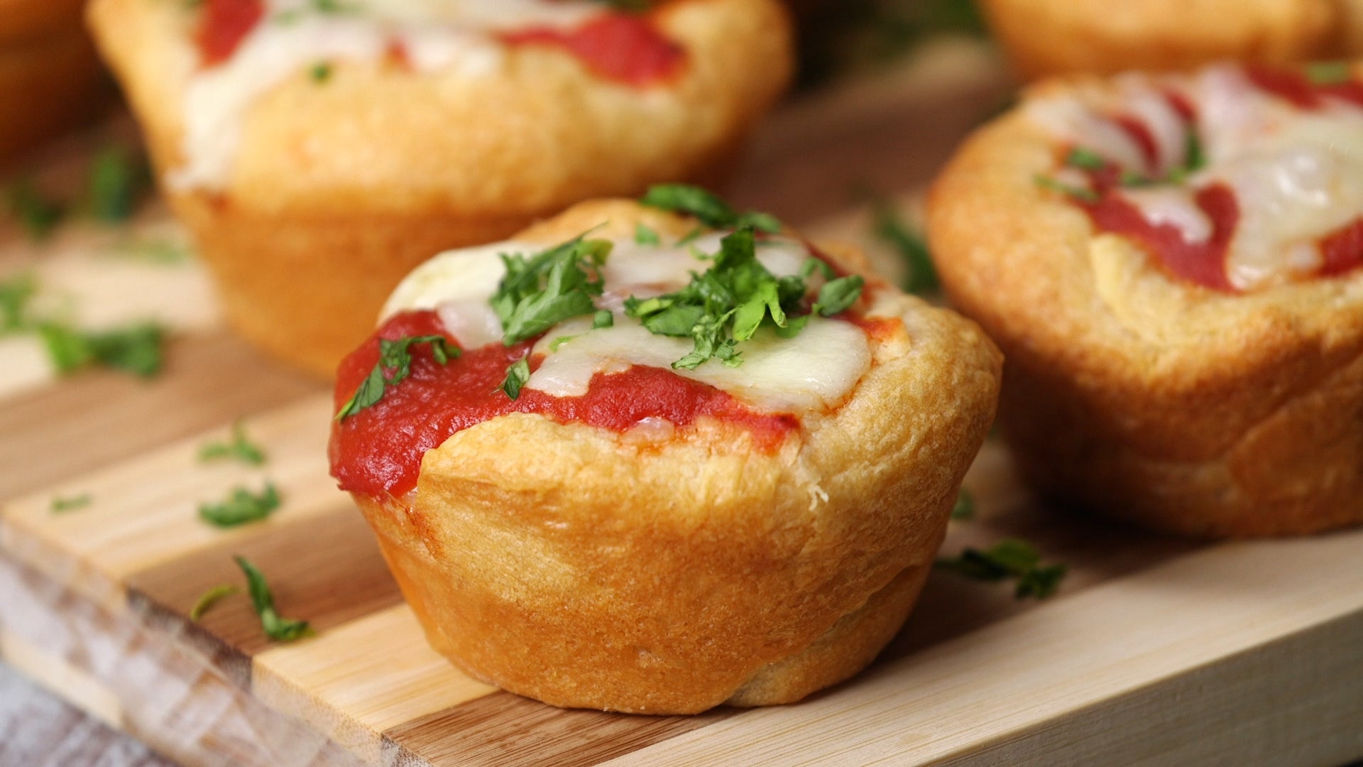 saucy high protein tomato basil sauce oozes out of a cheese burst muffin garnished with fresh basil placed on a wooden tray.